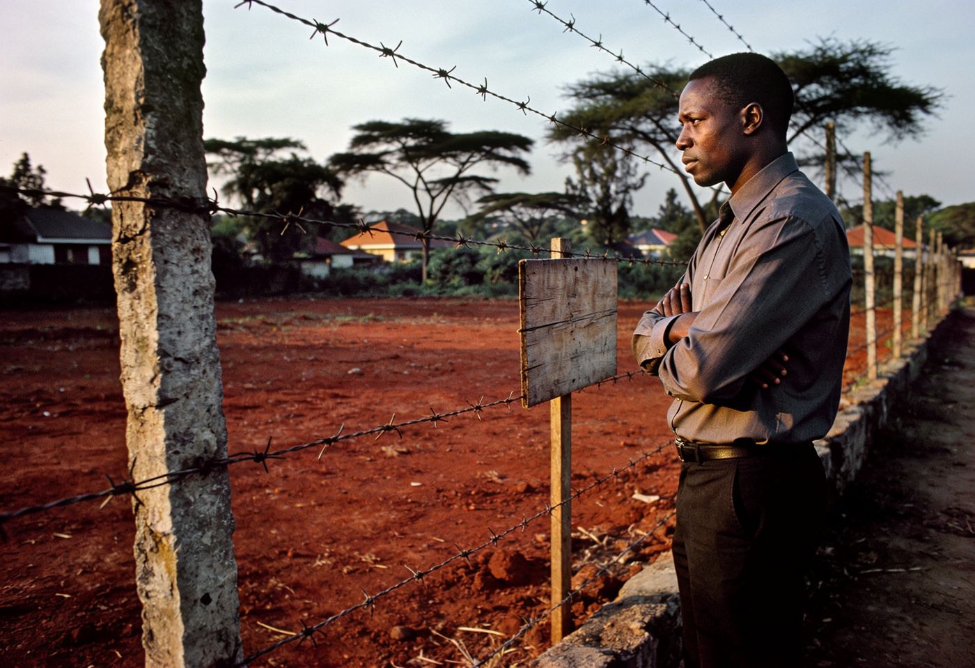 Buyer carefully inspecting a fenced vacant plot of red-earth land in a leafy Nairobi suburb before purchase
