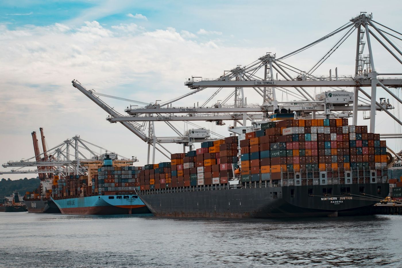 Container ships being loaded with colorful shipping containers at a port — sea freight to Mombasa takes four to eight weeks